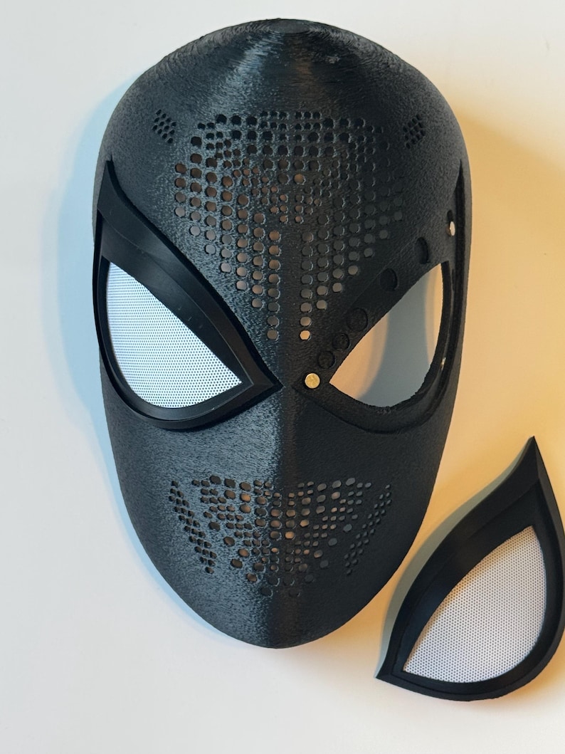 Puede incluir: Una m&aacute;scara negra texturizada con cubiertas oculares de malla blanca y una pieza ocular separada. La m&aacute;scara tiene un dise&ntilde;o perforado en las secciones superior e inferior. Probablemente para cosplay o disfraces.