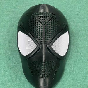 May include: Black Spider-Man mask with white mesh eye coverings and a perforated design on the forehead and mouth area. The mask is made of a matte black material and is likely a costume accessory.