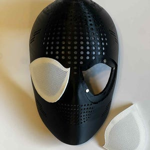 Puede incluir: M&aacute;scara negra con cubiertas oculares de malla blanca y una pieza de malla blanca separada. La m&aacute;scara tiene un dise&ntilde;o perforado y es probablemente para cosplay o disfraces.