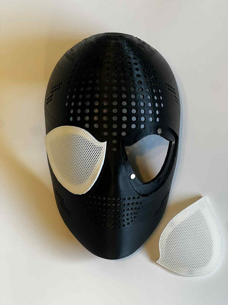 Puede incluir: M&aacute;scara negra con cubiertas oculares de malla blanca y una pieza de malla blanca separada. La m&aacute;scara tiene un dise&ntilde;o perforado y es probablemente para cosplay o disfraces.