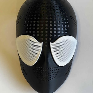 Puede incluir: Una m&aacute;scara negra con cubiertas oculares de malla blanca. La m&aacute;scara tiene una serie de peque&ntilde;os orificios de ventilaci&oacute;n circulares y rectangulares. La m&aacute;scara est&aacute; dise&ntilde;ada para cubrir la cara.