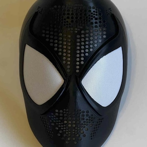 May include: Black Spider-Man mask with white mesh eye coverings. The mask has a textured surface with small circular perforations around the mouth and forehead. A superhero costume accessory.