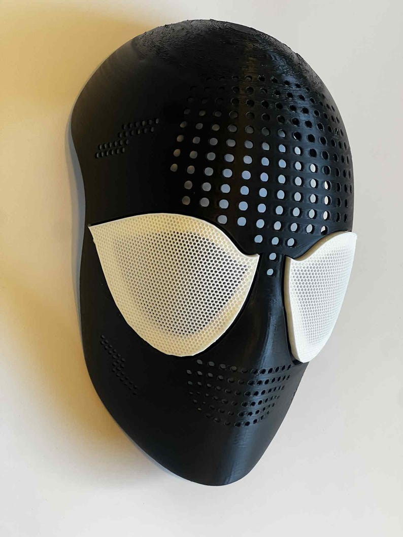 Puede incluir: Una m&aacute;scara negra con cubiertas oculares de malla blanca. La m&aacute;scara tiene una serie de peque&ntilde;os agujeros espaciados uniformemente en la parte superior y los lados. Las cubiertas oculares son de un blanco brillante, contrastando con el negro.