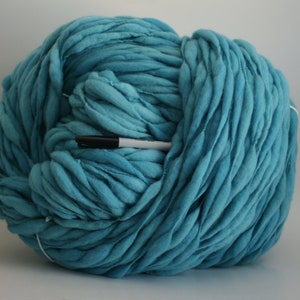 May include: A large ball of teal blue chunky yarn. The yarn is made of soft, thick fibers and is perfect for knitting or crocheting.