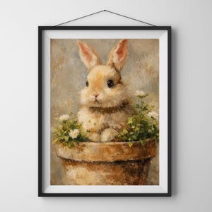 Puede incluir: Impresión enmarcada de un conejo en una maceta. El conejo tiene pelaje marrón y ojos oscuros. La maceta es marrón y las flores son blancas con hojas verdes. El fondo es de un color suave y neutro.