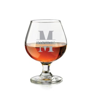 May include: A clear glass brandy snifter with a personalized engraving. The engraving features the letter "M" and the name "Marshall".
