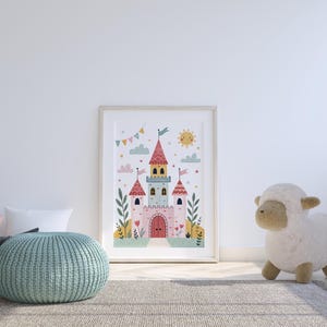 K&ouml;nnte beinhalten: Gerahmte Illustration eines skurrilen Schlosses mit rosa, blauen und gelben T&uuml;rmen, Flaggen und einer l&auml;chelnden Sonne. Das Kunstwerk wird in einem hellen Holzrahmen pr&auml;sentiert. Ein hellblaues Strickpouf und ein Stoffschaf befinden sich im Vordergrund.