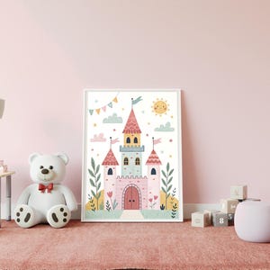 K&ouml;nnte beinhalten: Gerahmte Illustration eines skurrilen Schlosses mit rosa, blauen und gelben Akzenten. Das Kunstwerk zeigt eine l&auml;chelnde Sonne, Wolken und bunte Fahnen, passend f&uuml;r ein Kinderzimmer. Das Bild ist vor einer rosa Wand platziert.
