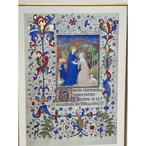 May include: A framed medieval manuscript illumination featuring a central scene of two figures in robes, one blue and one beige, with a small white dog. The border is decorated with intricate gold, red, and blue floral motifs and Latin text.