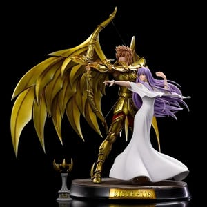 May include: A detailed figurine of a golden armored archer with a bow and arrow, standing beside a woman in a white dress with flowing purple hair. The base reads "Sisyphus". A small golden emblem is on the left.