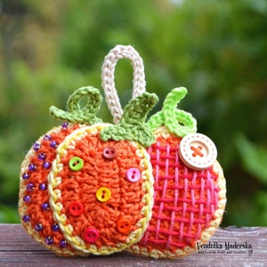 Könnte beinhalten: Ein gehäkelter Kürbis-Anhänger mit einer Schlaufe zum Aufhängen. Der Kürbis ist orange mit gelben und grünen Akzenten. Er hat eine Vielzahl von bunten Knöpfen und Perlen.