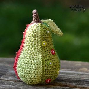 May include: A crocheted pear with a green, brown and red colour scheme. The pear has a brown stem and is decorated with colourful buttons.
