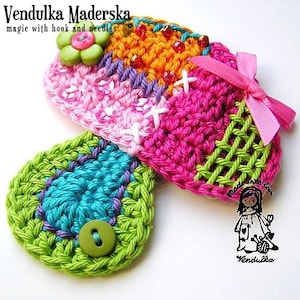 May include: A colorful crocheted butterfly brooch with a green button, pink ribbon, and sequins. The brooch is made with different colored yarns, including pink, green, blue, and orange.