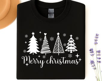 Könnte beinhalten: Schwarzes Sweatshirt mit einem weißen Aufdruck von vier Weihnachtsbäumen, Schneeflocken und dem Schriftzug "Merry Christmas". Im Hintergrund sind ein Hut und ein Lavendelzweig zu sehen.