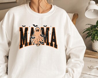 May include: White sweatshirt with the word "MAMA" in black and orange block letters. A checkered ghost graphic is centered within the word "MAMA". Small black bats are above the word "MAMA".