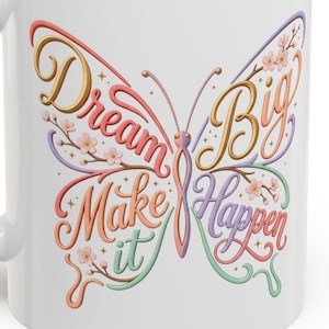 May include: White ceramic mug with a purple interior and handle. The mug features a colourful butterfly design with the words "Dream Big Make it Happen" in a script font. Floral accents are included in the design.