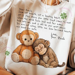 以下が含まれることがあります： 2匹のぬいぐるみ猿のグラフィックと手書きのテキストが特徴のクリーム色のスウェットシャツ。テキストは「Dear Punch, I am not breath, not a beating heart...」と「Love, Your Plush」です。