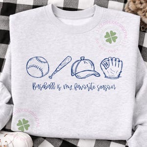 K&ouml;nnte beinhalten: Hellgraues Sweatshirt mit marineblauem Baseball-Design. Das Design umfasst einen Baseball, einen Schl&auml;ger, eine Kappe und einen Handschuh mit dem Text "Baseball is my favorite season."