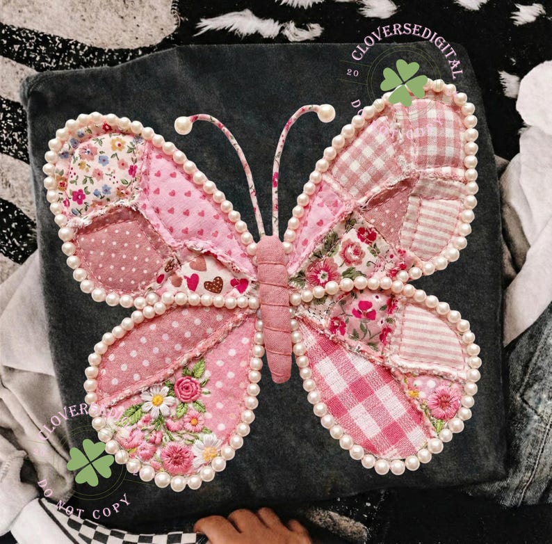 May include: A decorative butterfly made of pink fabric patches with floral, polka dot, and gingham patterns. The butterfly is outlined with faux pearls and has embroidered details. The wings are in shades of pink and white. The background is a dark gray fabric.