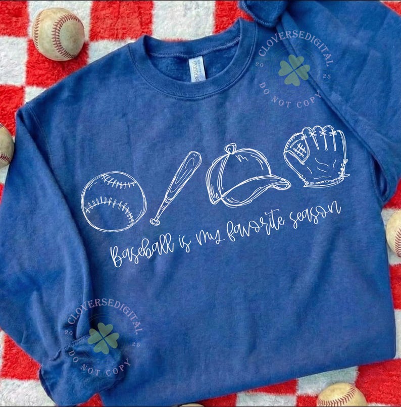 K&ouml;nnte beinhalten: Ein marineblaues Sweatshirt mit Baseball-Motiv. Das wei&szlig;e Design zeigt einen Baseball, einen Schl&auml;ger, eine Kappe und einen Handschuh mit dem Text "Baseball is my favorite season". Der Hintergrund ist ein rot-wei&szlig; kariertes Muster.