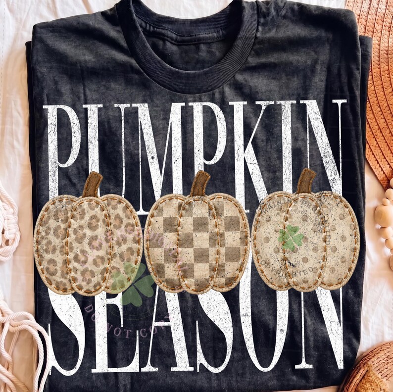 May include: A black short-sleeve t-shirt featuring the white distressed text PUMPKIN SEASON. Three illustrated pumpkins are centered, each with a unique pattern: one with a leopard print, one with a checkered pattern, and one with polka dots.