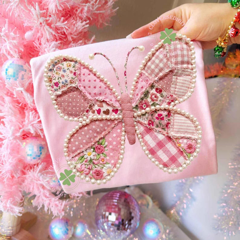May include: A pink butterfly applique with pearl bead trim is centered on a pink fabric. The butterfly wings are made of various pink patterned fabrics, including polka dots, floral prints, and gingham. The antennae have small pearl beads at the tips.