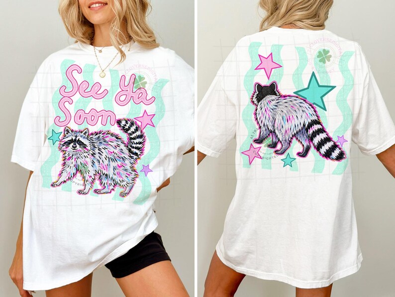 May include: White t-shirt featuring a colorful raccoon illustration with the text "See Ya Soon." The design includes pink stars and teal wavy lines. The back of the shirt has a similar design with a raccoon and stars.