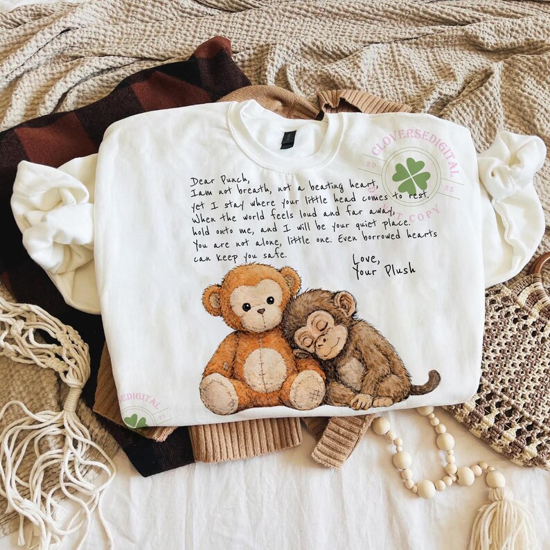 May include: White sweatshirt with a crew neck featuring a watercolor illustration of two monkeys and the text "Dear Punch". The sweatshirt has a relaxed fit and is made of a soft material. The design includes a four-leaf clover.