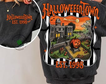 May include: A charcoal gray sweatshirt featuring a large back graphic of a spooky town with a pumpkin, the text HALLOWEENTOWN and EST. 1998 in orange. The front chest displays the same text in a smaller size. The design includes black and white stripes.