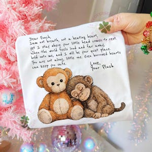 May include: White square fabric with a printed illustration of two plush monkeys and handwritten text. One monkey is light brown, the other is dark brown. The text reads "Dear Punch...Love, Your Plush."