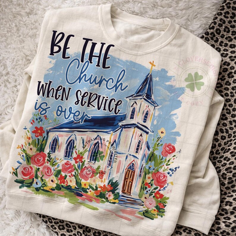 May include: Cream-colored sweatshirt with a church illustration and the text "BE THE Church WHEN SERVICE is OVER." The design features a white church with a blue roof, surrounded by colorful flowers.