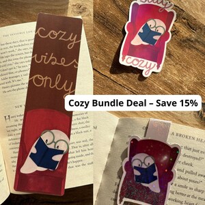 Op de afbeelding: Een bundel gezellige bladwijzers en stickers. Eén bladwijzer toont een spook dat in een stoel leest, met de tekst "cozy vibes only". Een sticker heeft een vergelijkbaar ontwerp. De tekst "Cozy Bundle Deal - Save 15%" is ook zichtbaar.