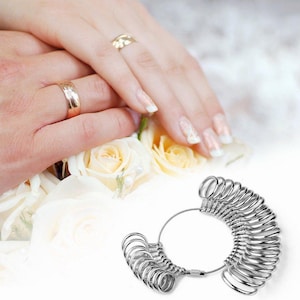 Op de afbeelding: Een set zilveren ringmaten naast handen met gouden trouwringen. De handen rusten op een boeket witte en gele rozen. De ringmaten zitten op een draadlus.