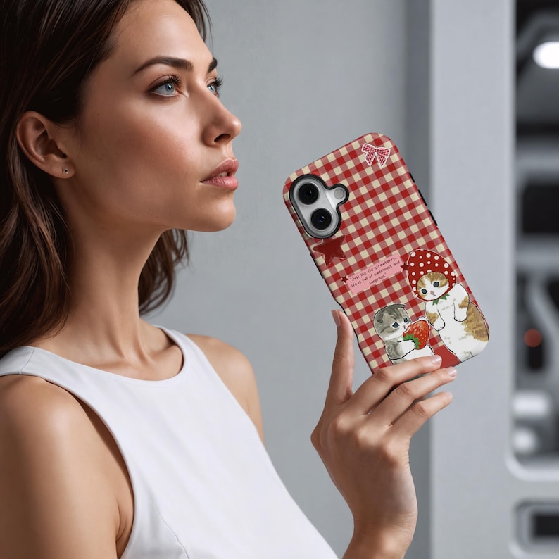 May include: A phone case with a red and white gingham pattern, decorated with illustrations of cats and strawberries. The case has a bow and star design. Text on the case reads "Just eat the strawberry, life is a lot of sweetness and happiness."