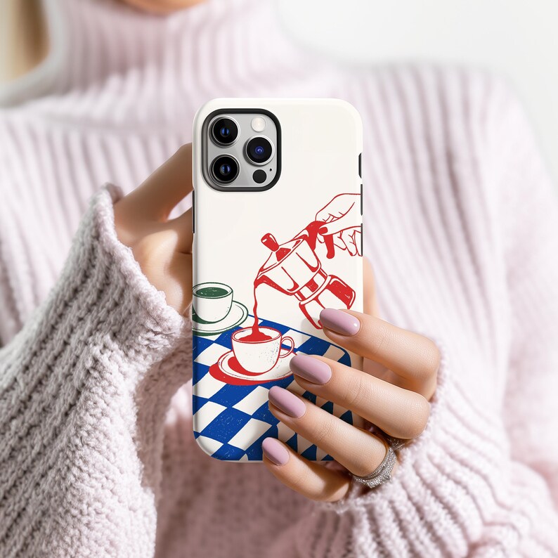 May include: A white phone case with a red and blue illustration of a coffee pot pouring coffee into a cup. The design includes a blue and white checkered pattern and a green cup. The case is held in a person's hands.