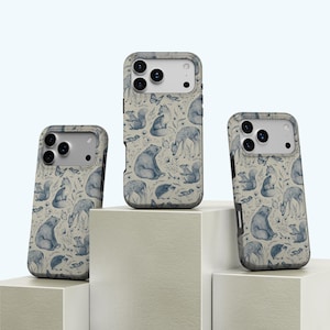 Könnte beinhalten: Drei Handyhüllen mit einem Design zum Thema Natur. Die Hüllen zeigen ein sich wiederholendes Muster aus blauen Waldtieren, darunter Bären, Füchse und Eichhörnchen, vor einem neutralen Hintergrund. Die Hüllen werden auf einer weißen Oberfläche präsentiert.