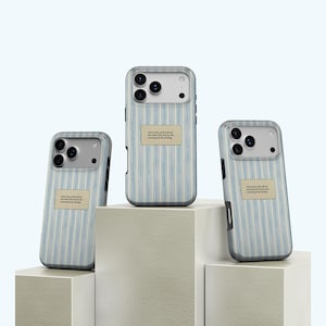 May include: Three mobile phone cases with a blue and white striped design. Each case features a rectangular label with text. The cases are presented on white geometric blocks against a light blue backdrop.