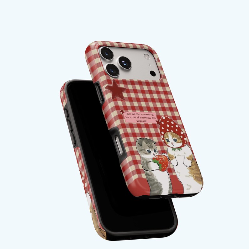 May include: A phone case with a red and white gingham pattern. The case features an illustration of two cats, one holding a strawberry. Text on the case reads, "Just like the strawberry, life is full of sweetness and surprises."