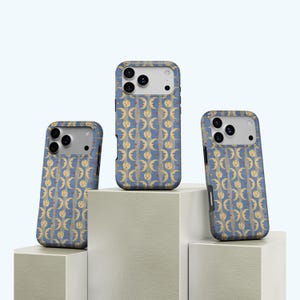 May include: Three phone cases with a blue background and a repeating pattern of yellow moons, stars, and faces. The cases are displayed on white geometric blocks, showcasing the design.