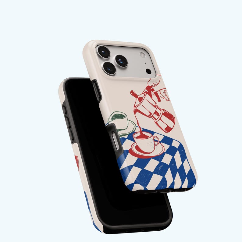 May include: A phone case with a cream-coloured background. It features a red and blue illustration of a coffee pot pouring coffee into a cup on a blue and white chequered tablecloth. Another phone case is visible.