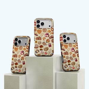 Puede incluir: Tres fundas para teléfono con un patrón repetido de varios productos de panadería, incluyendo gofres, galletas y pasteles, sobre un fondo crema. Las fundas se muestran sobre bloques geométricos blancos, resaltando el diseño.