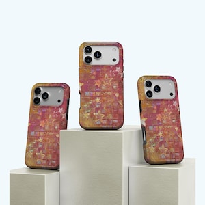 Könnte beinhalten: Drei Handyhüllen mit einem mosaikartigen Design aus Sternen und Quadraten in Rot-, Orange- und Goldtönen. Die Hüllen haben ein schützendes Stoßfängerdesign und einen Kameraausschnitt. Sie werden auf weißen geometrischen Blöcken präsentiert.