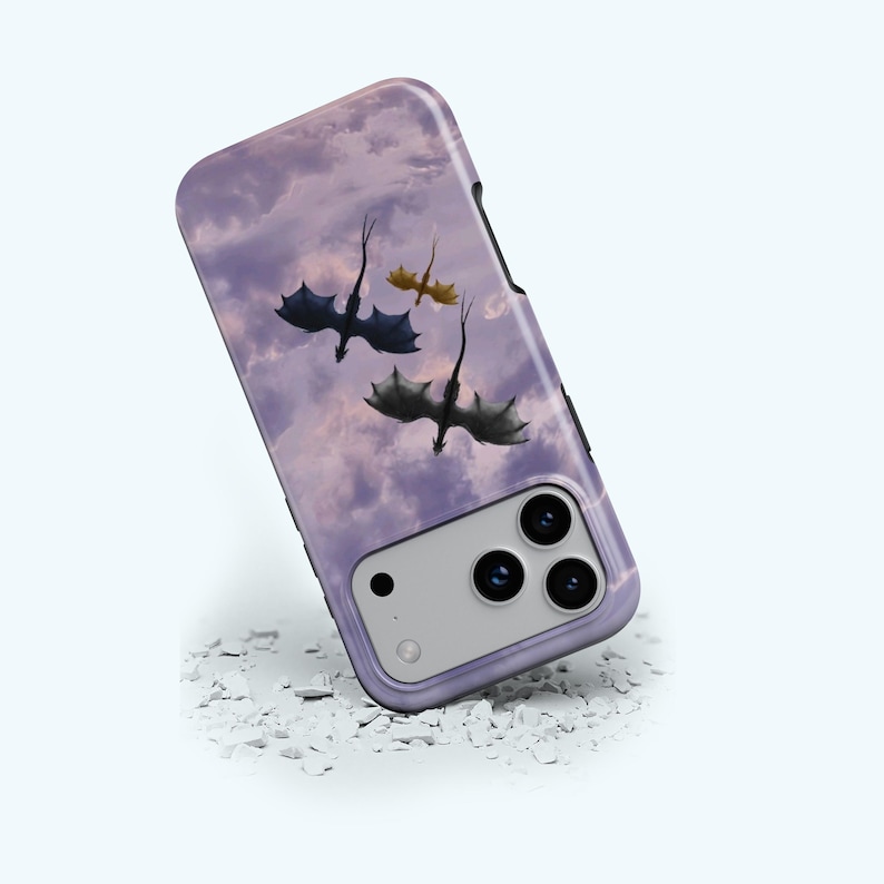 May include: A phone case featuring a purple sky with three dragons in flight. The dragons are in shades of black, gray, and gold. The case has a black border and a camera cutout.