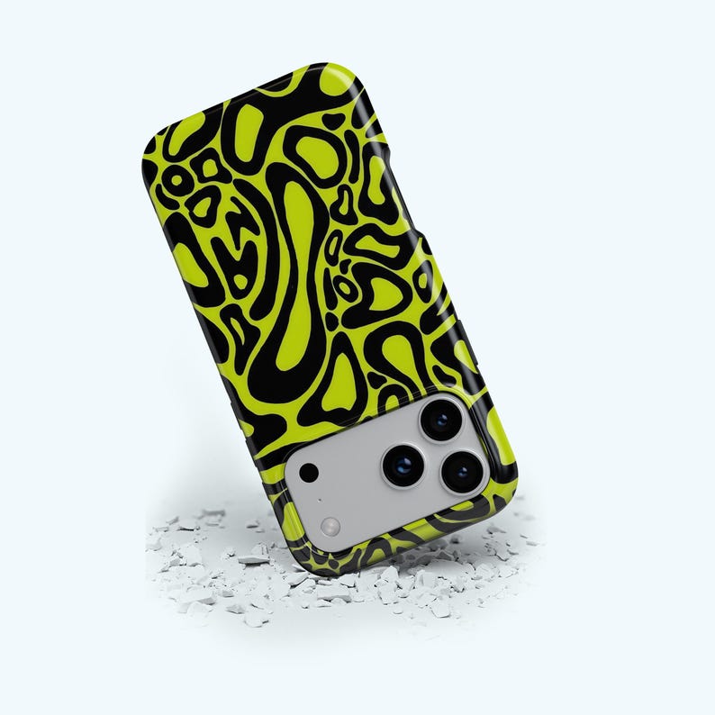 K&ouml;nnte beinhalten: Eine Handyh&uuml;lle mit einem neon-gr&uuml;nen und schwarzen Muster. Das Geh&auml;use hat ein sich wiederholendes abstraktes Design aus organischen Formen in Schwarz auf einem hellgr&uuml;nen Hintergrund. Die Handyh&uuml;lle hat einen Kameraausschnitt und liegt auf einer wei&szlig;en Oberfl&auml;che.