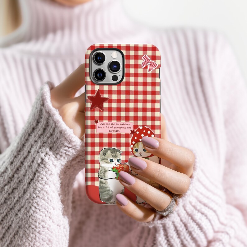 May include: A red and white gingham phone case with a cartoon illustration of two kittens and strawberries. The case has a red star and a bow design. Text on the case reads: "Just like the strawberry, life is full of sweetness and surprises."