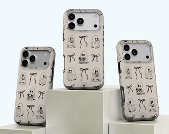 Puede incluir: Tres fundas de teléfono con un fondo beige y un patrón repetido de fantasmas negros dibujados a línea leyendo libros y atados con lazos. Las fundas tienen un borde transparente y un recorte para la cámara.