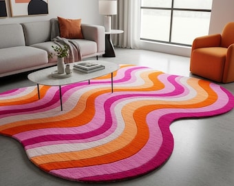 May include: A colorful area rug with a wavy design in shades of pink, orange, and white. The rug is placed on a gray floor in a living room setting. The rug's unique shape and vibrant colors add a modern touch to the room.