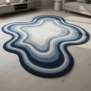 May include: A unique, abstract-shaped rug with a layered design in shades of blue and white. The rug features a wavy, organic form, creating a modern and stylish accent for any room. The color palette includes navy, light blue, and white.