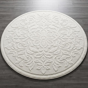 May include: A round, off-white rug with a floral pattern. The rug features a central flower design surrounded by leaves and other floral elements. The rug is made of a soft, textured material and is suitable for a living room or bedroom.