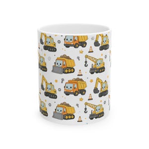 May include: White ceramic mug featuring a repeating pattern of cartoon construction vehicles. The design includes yellow excavators, orange dump trucks, and yellow cranes, along with traffic cones and stars. A fun, playful design.